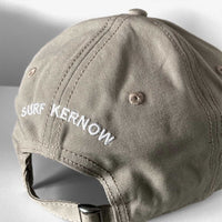 Back shot of our stone-coloured organic Cotton Baseball Cap with embroidered 'Surf Kernow' text above the adjustable strap and buckle – designed and embroidered in Cornwall.